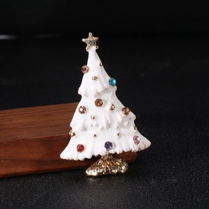 Macro shot of white enamel Christmas tree brooch with colorful rhinestones on wood