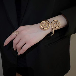 Detail view of bold gold spiral cuff bracelet and matching ring on model with black suit