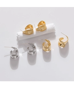 Macro detail of irregular wave geometric earrings in shiny gold, silver and matte gold finishes