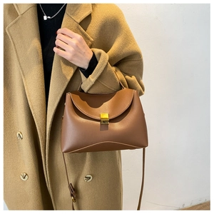 Close-up of a brown leather handbag featuring a minimalist square gold lock and flap design
