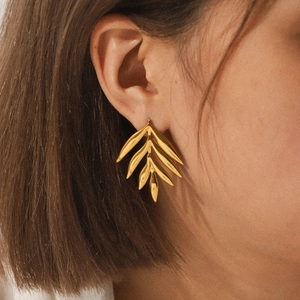 Minimalist 18K gold plated stainless steel leaf stud earrings worn by a model