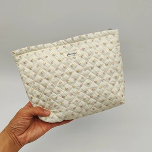 Detailed close-up of quilted floral cosmetic bag with pink flowers and blue dots pattern