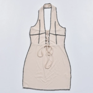 Détail de la robe licou en tricot beige avec laçage frontal et coutures contrastées noires