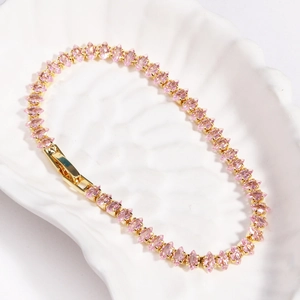 Detail of pink marquise-cut zircon stones set in a gold chain on a ceramic plate