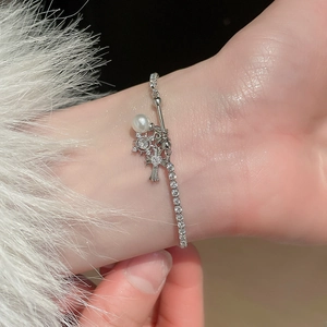 Close-up of silver fleur-de-lis cross bracelet with zircon stars and pearls on a wrist