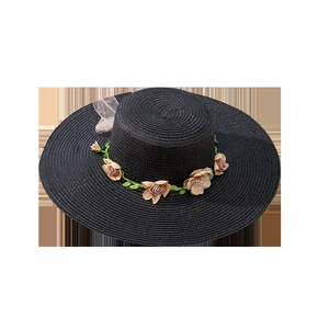 Women's black wide-brim straw sun hat with decorative floral wreath and ribbon