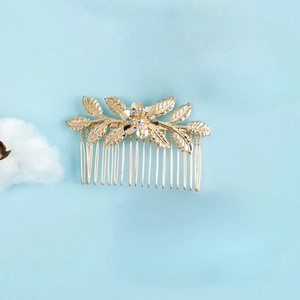 Golden metal hair comb with leaf and floral design featuring rhinestone center accents