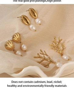 Detail of PVD gold plated shell and coral earrings with pearls on soft beige fabric