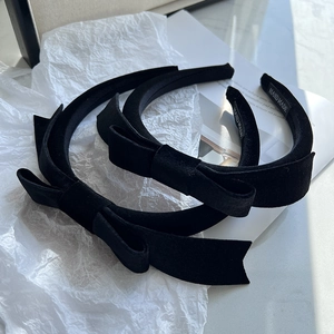 Set of two black velvet bow headbands featuring handmade labels on white magazine