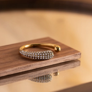 Macro view of gold-plated bangle with pavé-set zircons and polished spherical end