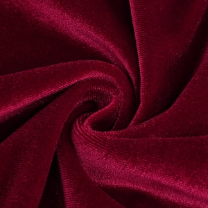 Detailed close-up of dark red velvet fabric with elegant draped folds and soft sheen
