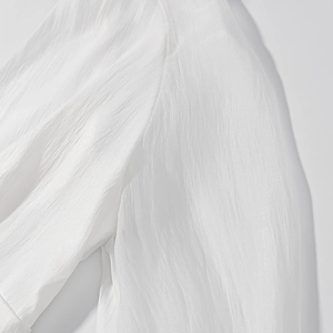 Close-up of the white shirt fabric showing vertical pleated texture and light sheen