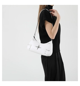 Close-up of white shoulder bag with silver rivets and metal star detail on model