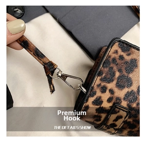 Detail of silver-tone metal swivel hook and leopard print shoulder strap on small bag