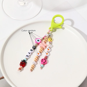 Détail d'un porte-clés en perles colorées avec smileys et lettres sur plat blanc
