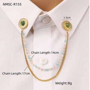Detail of gold double chain collar pin with green natural stone on white shirt