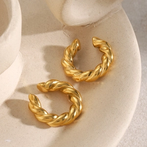 Boucles d'oreilles clips torsadées en acier inoxydable doré 18 carats sur plateau