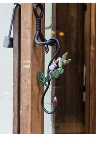 Detailed view of hand-painted hummingbird on a cast iron S-shaped wall hook