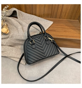 Detail of black V-quilted shell bag with gold hardware and elegant stitching texture