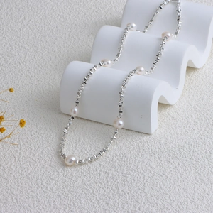 Detail of freshwater pearl necklace with geometric silver beads on a white wave display