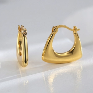 Macro shot of geometric gold earrings with polished mirror finish and minimal trapezoid shape