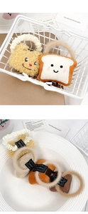 Detail of plush yellow bear and toast bread hair ties in a decorative white basket