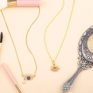 Gold Evil Eye necklaces with blue zircon and eyelash pendants in a lifestyle setting