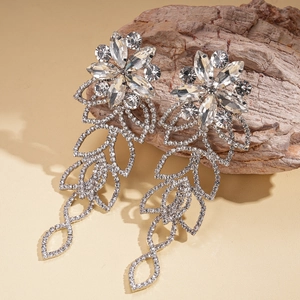Close-up of silver hollow floral earrings with crystals on rustic wood background