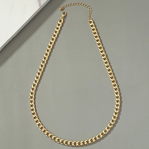 Detailed view of a gold Cuban link chain necklace on a premium marble surface