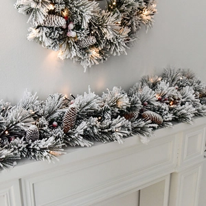 Flocked Christmas garland and wreath with pine cones, red berries and warm LED lights