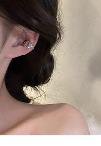 Detail view of a silver cuff earring featuring letter M design and sparkling zircons