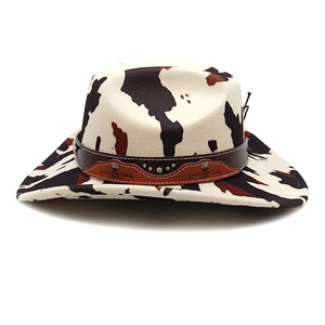 Detail of cow print cowboy hat featuring a leather band with metal studs and ornate inlay