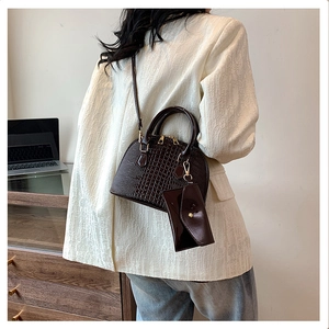Brown crocodile embossed shell bag shown worn by a model in a modern office setting