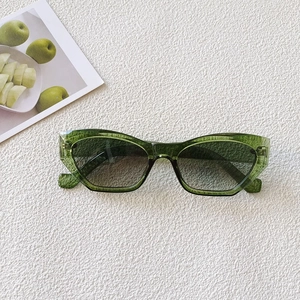 Close-up of retro oval sunglasses with translucent green frames and gradient grey lenses