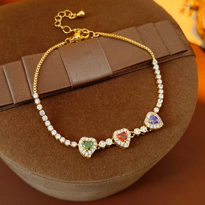 Macro view of 18k gold plated bracelet with colorful heart zircons on velvet