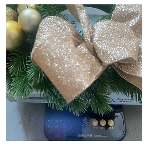 Close-up of a Christmas wreath with golden balls, pine needles, and champagne sequin bow
