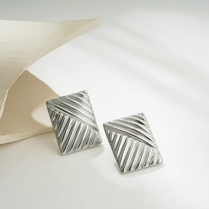 Macro detail of silver square earring showing linear wave texture and metallic finish
