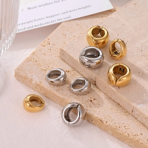 Minimalist gold and silver thick hoop earrings displayed on a natural textured stone surface