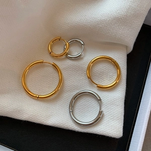 Macro shot of gold and silver two-tone round hoop earrings on white fabric texture