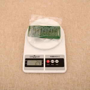 Close-up of green plastic Christmas ornament hooks on a digital scale weighing 24g