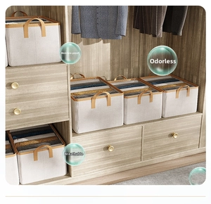 Detail view of foldable beige fabric organizers with brown leather handles in a wooden closet