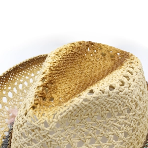 Detail of hand-woven straw hat showing top weave pattern and decorative tassels