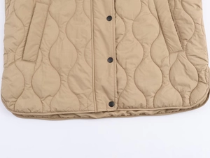 Detailed close-up of khaki quilted vest with wavy stitching and black snap buttons