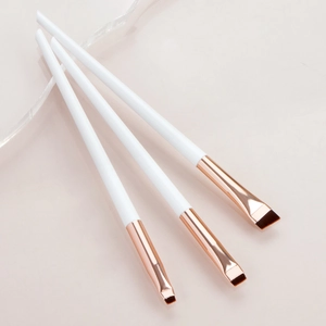 Detailed close-up of three angled eyeliner brushes with white handles and rose gold ferrules