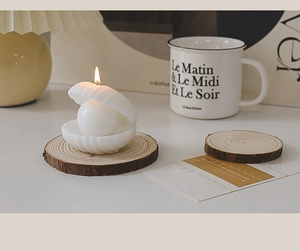 Close-up of shell-shaped candle on natural wood base in a cozy aesthetic setting