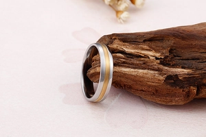 Détail macro d'une bague en acier bicolore avec texture brossée sur décor en bois