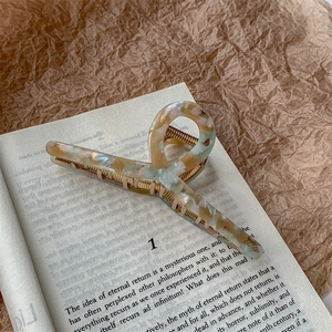 Detail of marble-patterned cellulose acetate hair claw clip with golden metal springs