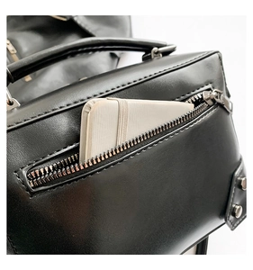 Close-up of black rivet motorcycle bag showing functional side zipper pocket and texture