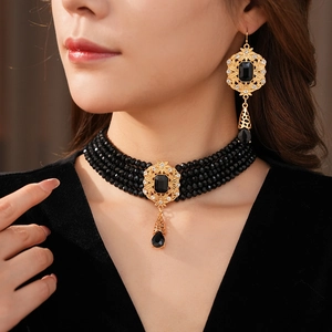 Detail of vintage palace style choker and earrings set with black beads and gold frame