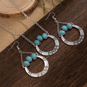 Detail view of boho antique silver necklace and turquoise earrings on a rustic wood background